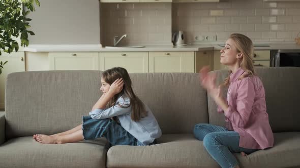 Beautiful Young Mother is Scolding Her Daughter While Sitting on Sofa at Home alt
