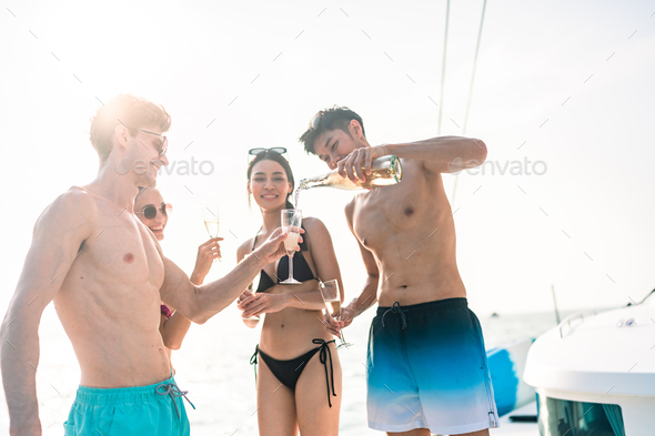 Friends group drink a champagne at outdoor party yacht. Attractive young men and women hanging out