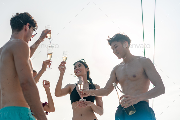 Friends group drink a champagne at outdoor party yacht. Attractive young men and women hanging out