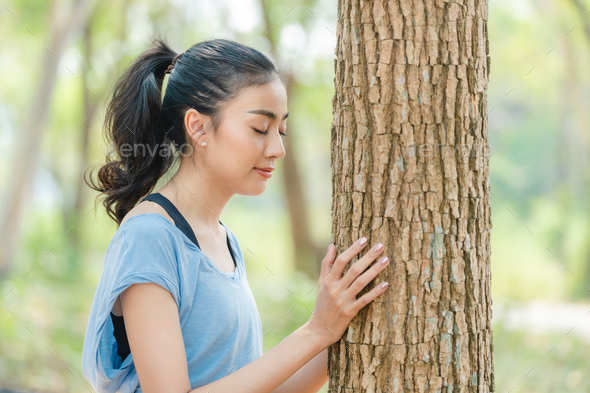 Asian woman using hands to hugging a tree in forest, Environment earth day or green sustainable