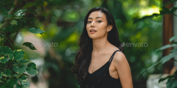 Beautiful girl in the garden on a sunny day, sexy Asian woman wearing black  dress and posing Stock Photo by ckstockphoto