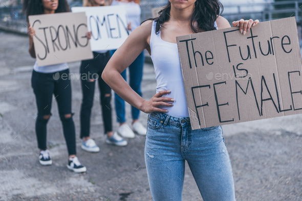 cropped view of girl holding placard with the future is female letters while standing with hand on