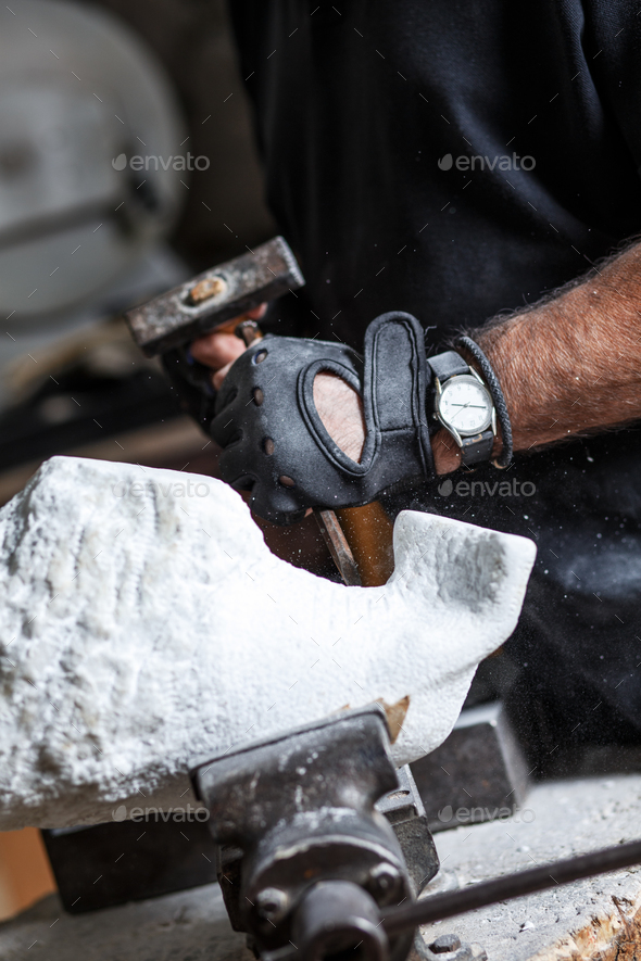 Close up of senior sculptor hands working on his marble sculpture in his workshop.
