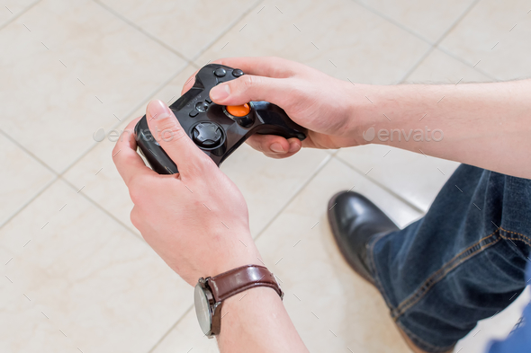 Close-up. The gamer holds a gamepad in his hands. Plays video