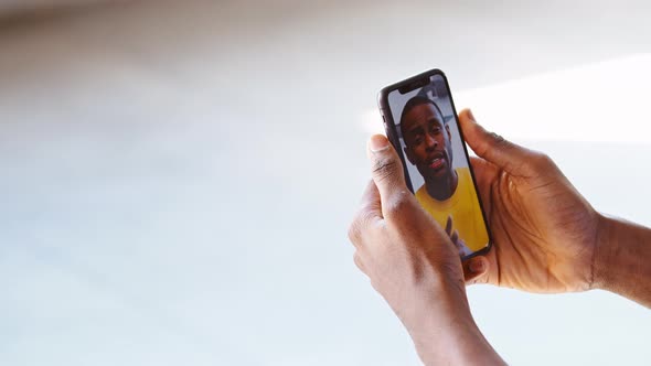 Male hands holding a smartphone in which a video call from a teacher alt