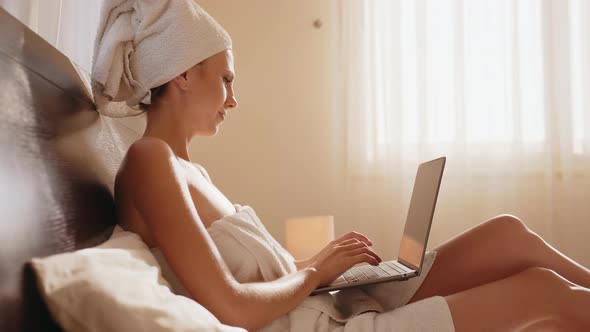 Woman Using Laptop While Lying on Comfy Bed at Hotel Room alt