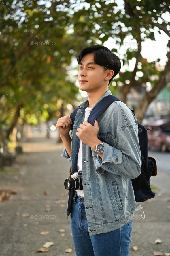 Happy asian man traveller in hipster outfit spending free time outdoors.  Stock Photo by prathanchorruangsak