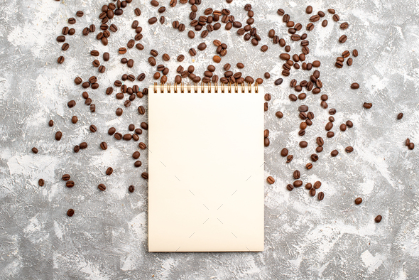 top view brown coffee seeds with notepad on white background coffee cocoa color copybook