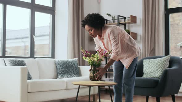 Woman Placing Flowers on Coffee Table at Home