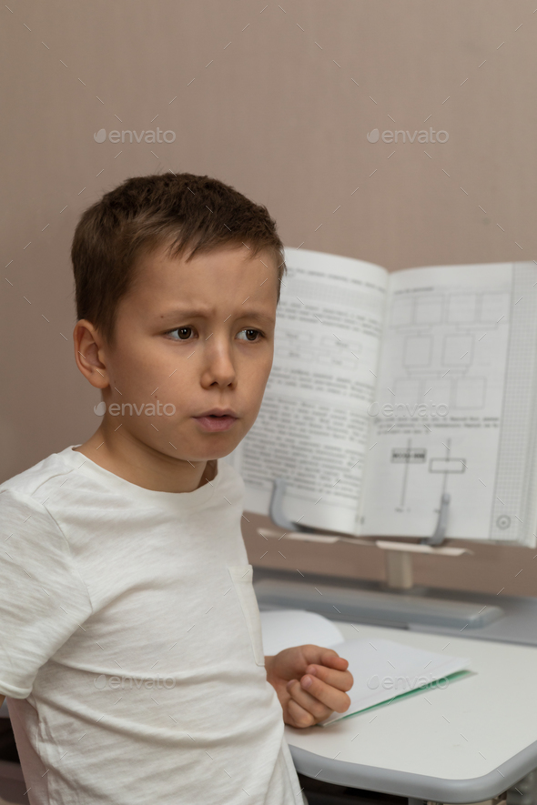 10-year-old schoolboy does homework, learns, thoughtfully memorizes new knowledge