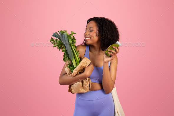 Glad millennial african american woman in sportswear hold jar of juice or smoothie and bag of
