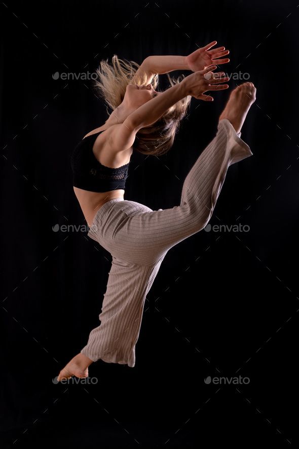 Vertical shot of a Caucasian young dancer performing a jump isolated on a black background