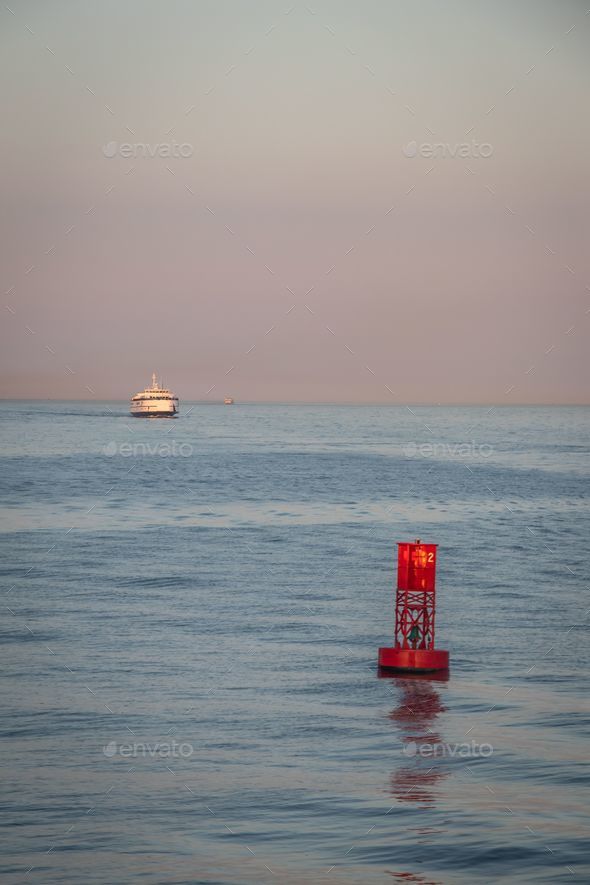 a red buoy in the water in the ocean with a small boat in the