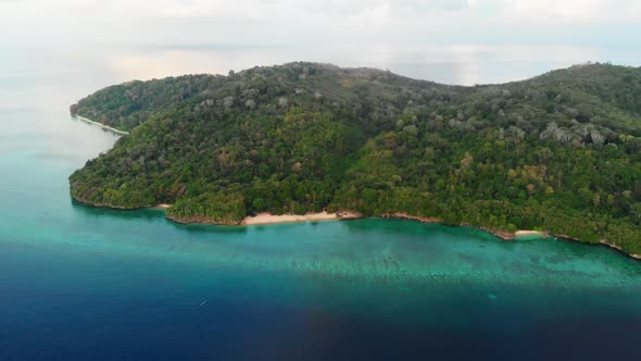 Aerial: flying over tropical Hatta island sand beach Banda Islands Indonesia alt