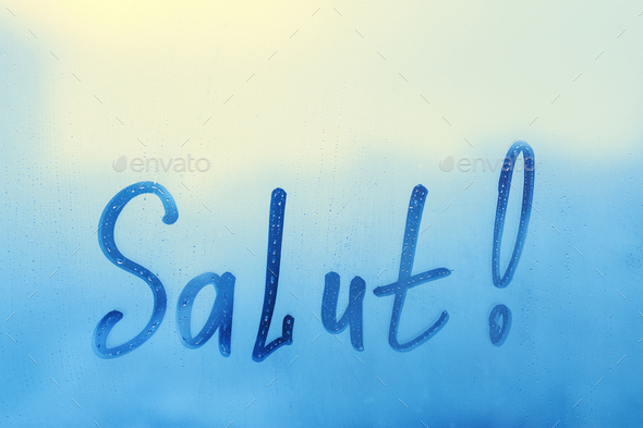 lettering Salut in French is hello in english on splashed by rain foggy glass on blue window