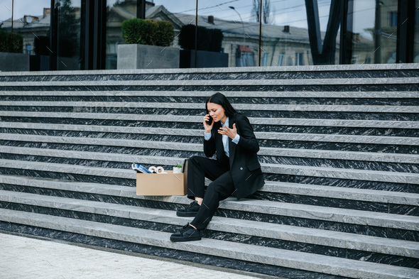 Troubled Woman Sitting on Stairs, Discussing Fired Job on Smartphone