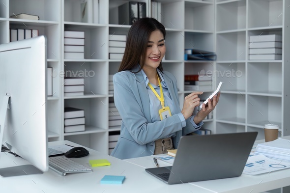 Happy businesswoman is using calculator to calculate company finances and taxes at her desk in