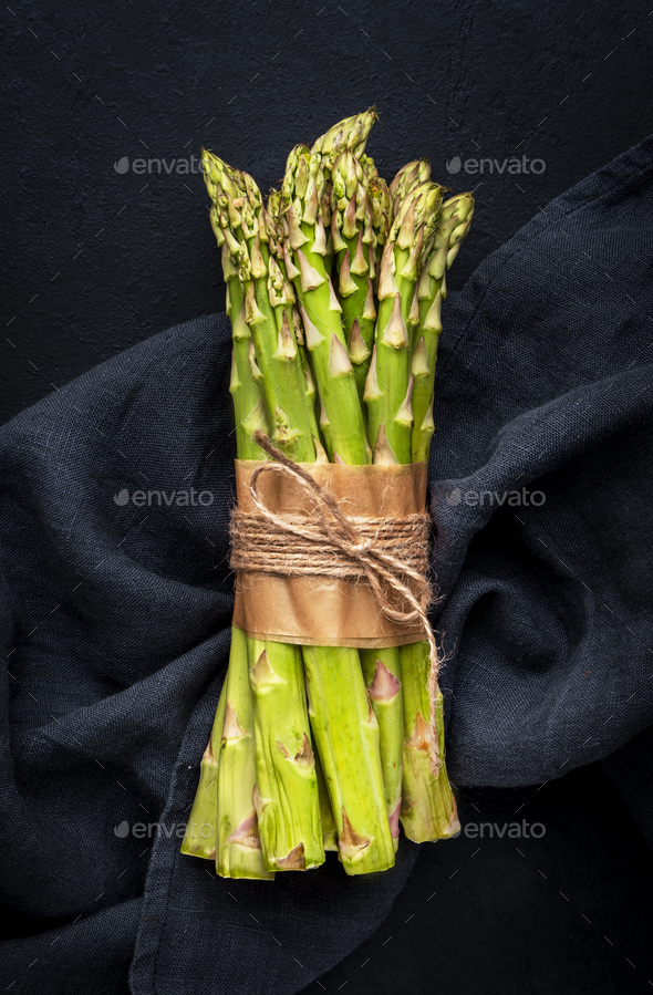 Green asparagus bunch on wicker tray on white table background