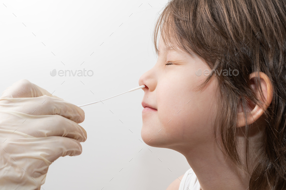 a swab into a childrens nose to collect COVID-19 sample