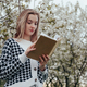 Portrait of Blonde Woman in Blossom Tree Flowers Holding Book in Hands. - PhotoDune Item for Sale