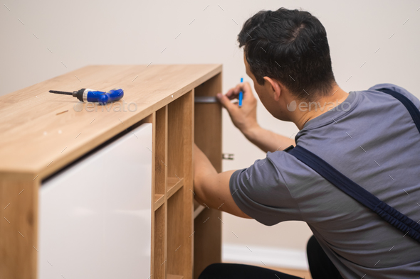 Furniture manufacturing and fixing carpenter hands installing shelves to wooden furniture