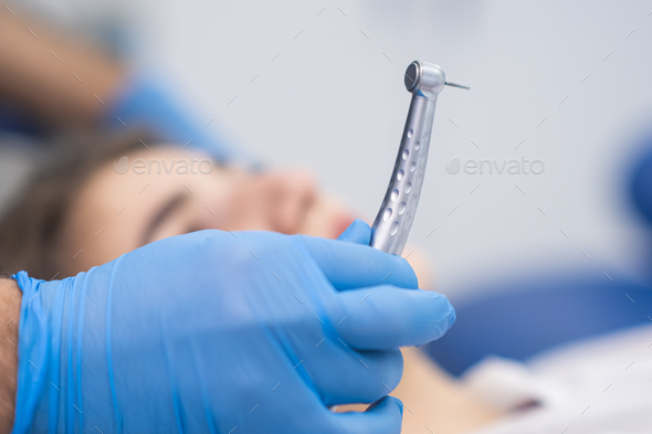 Professional dentistry services in clinic doctor in rubber gloves holding sterile dental drill