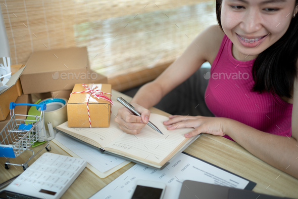 Woman is writing down the customer's details and addresses on the notebook - Stock Photo - Images