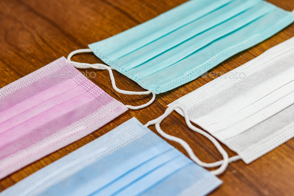 Selective focus shot of colorful surgical cotton masks on a wooden surface