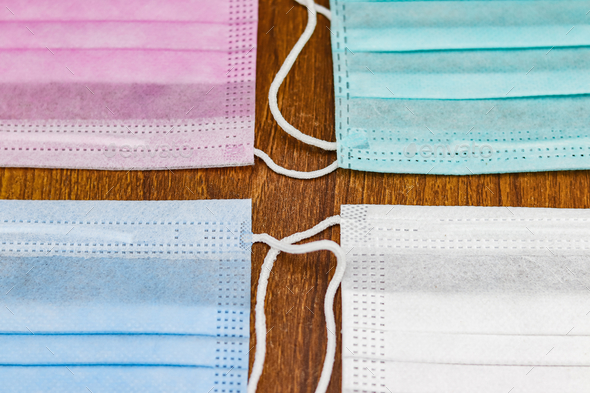 Top view shot of colorful surgical cotton masks on a wooden surface