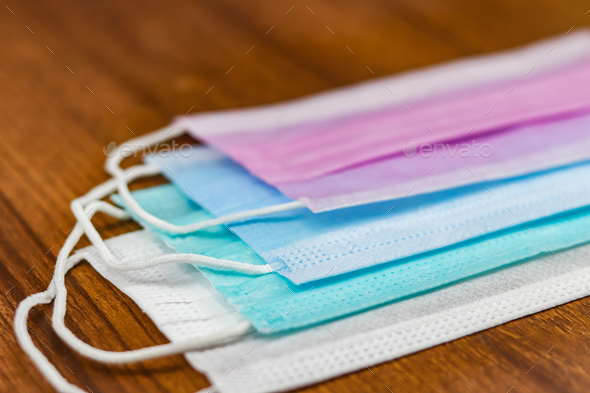 Selective focus shot of colorful surgical cotton masks on a wooden surface