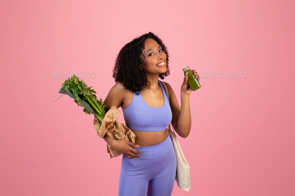 Happy millennial african american lady in sportswear hold jar of juice or smoothie and bag of