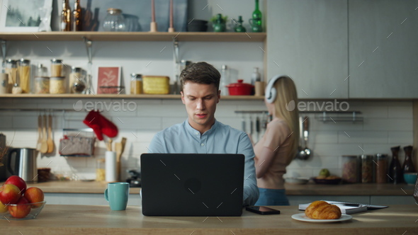 Manager have online meeting with clients on laptop at kitchen while wife cooking