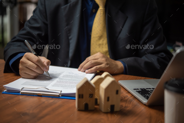 businessman holding a pen looking at documents Selling real estate,