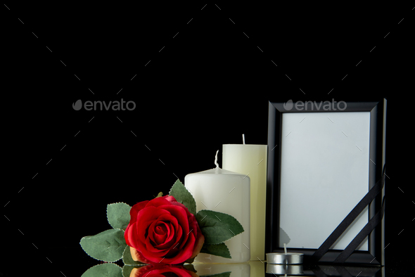 front view of white candles with picture frame on black background death funeral war