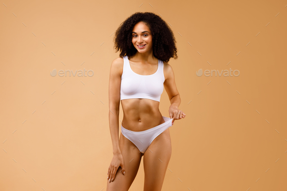 Healthy nutrition and belly health concept. Close up of woman flat stomach.  Black Blank Template female panties with copy space and mock up. Front  view. Cropped image, female bodycare isolated on gray