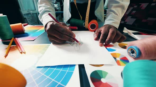 African Designer is Drawing a Dress on Paper alt