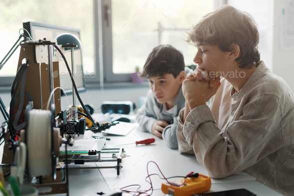 Young engineering students using a 3D printer
