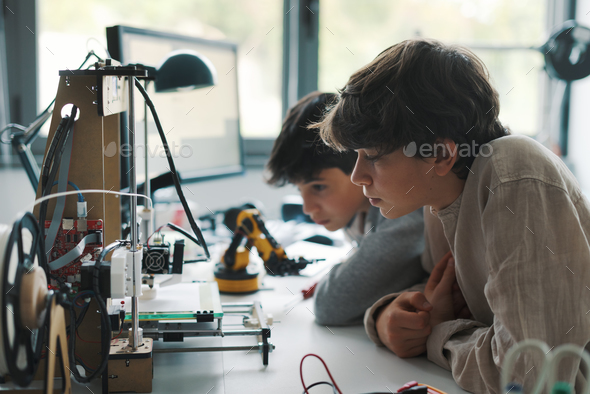 Young engineering students using a 3D printer