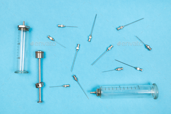 view of hypodermic needles and syringes on blue