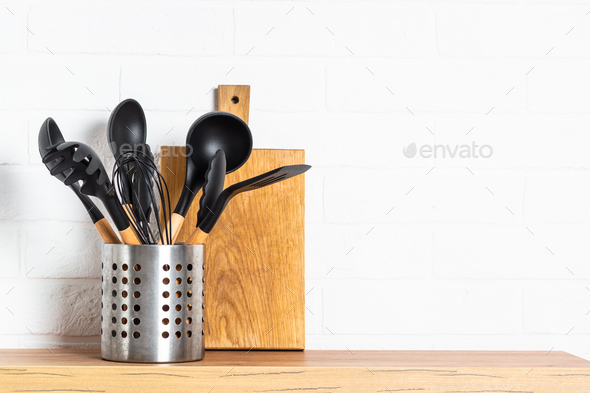 Cooking tools with wooden cutting boards, oil and shaker at white modern  kitchen interior. Stock Photo by Nadianb