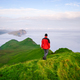 A tourist walks through the green hills on Mykines island, Faroe Islands - PhotoDune Item for Sale