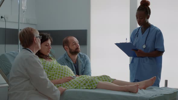 Doctor and African American Nurse Consulting Woman Expecting Child alt