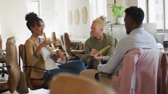 Happy diverse business people discussing with documents in creative office alt