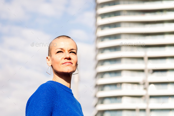 empowered woman with shaved head in cityscape - Stock Photo - Images