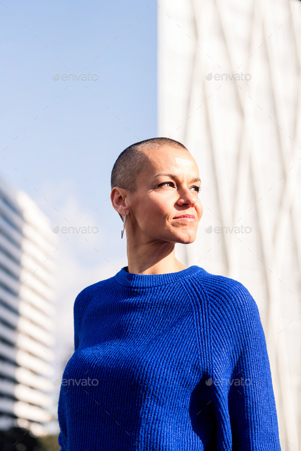 empowered woman with shaved head in cityscape - Stock Photo - Images