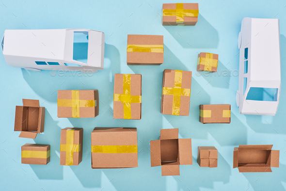 top view of cardboard boxes and white vans on blue background