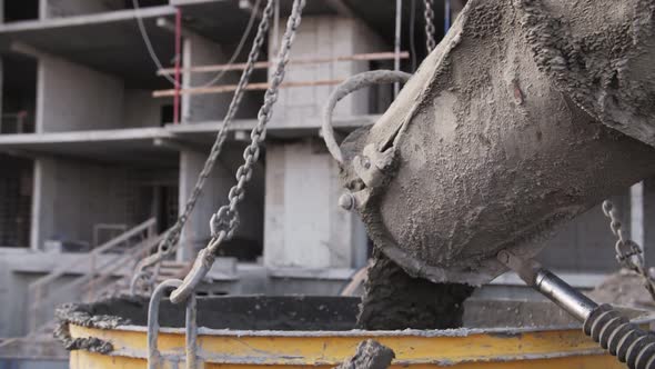 concrete pours from a concrete mixer at a construction site alt