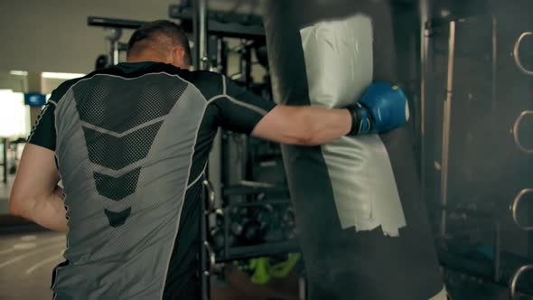 Strong Sporty Athlete Hitting Punching Bag Indoor of Gym alt