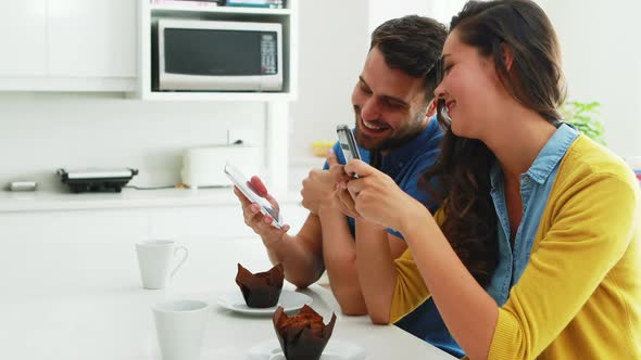Couple interacting with each other while using mobile phone alt