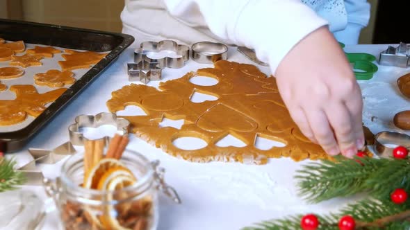 Child cuts heart shaped gingerbread cookie on table, dolly shot alt